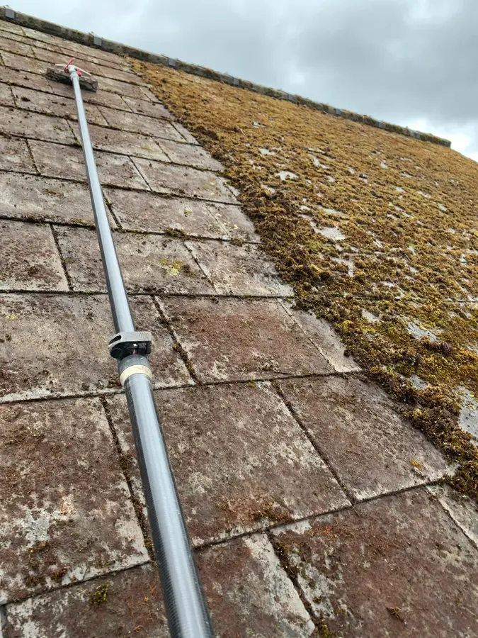 A roof-cleaning lance working across heavily mossed slate