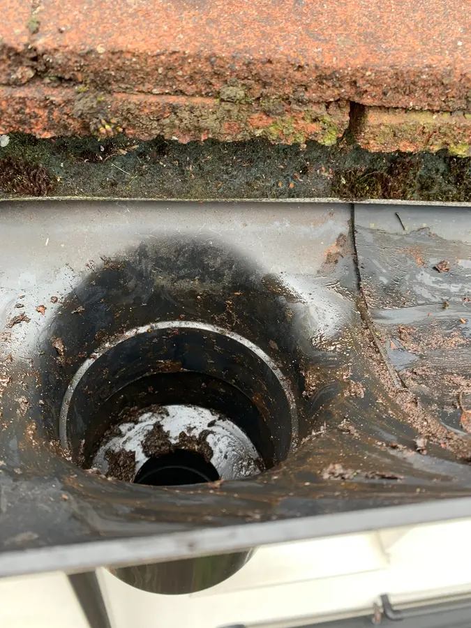 A gutter outlet completely blocked with silt and debris